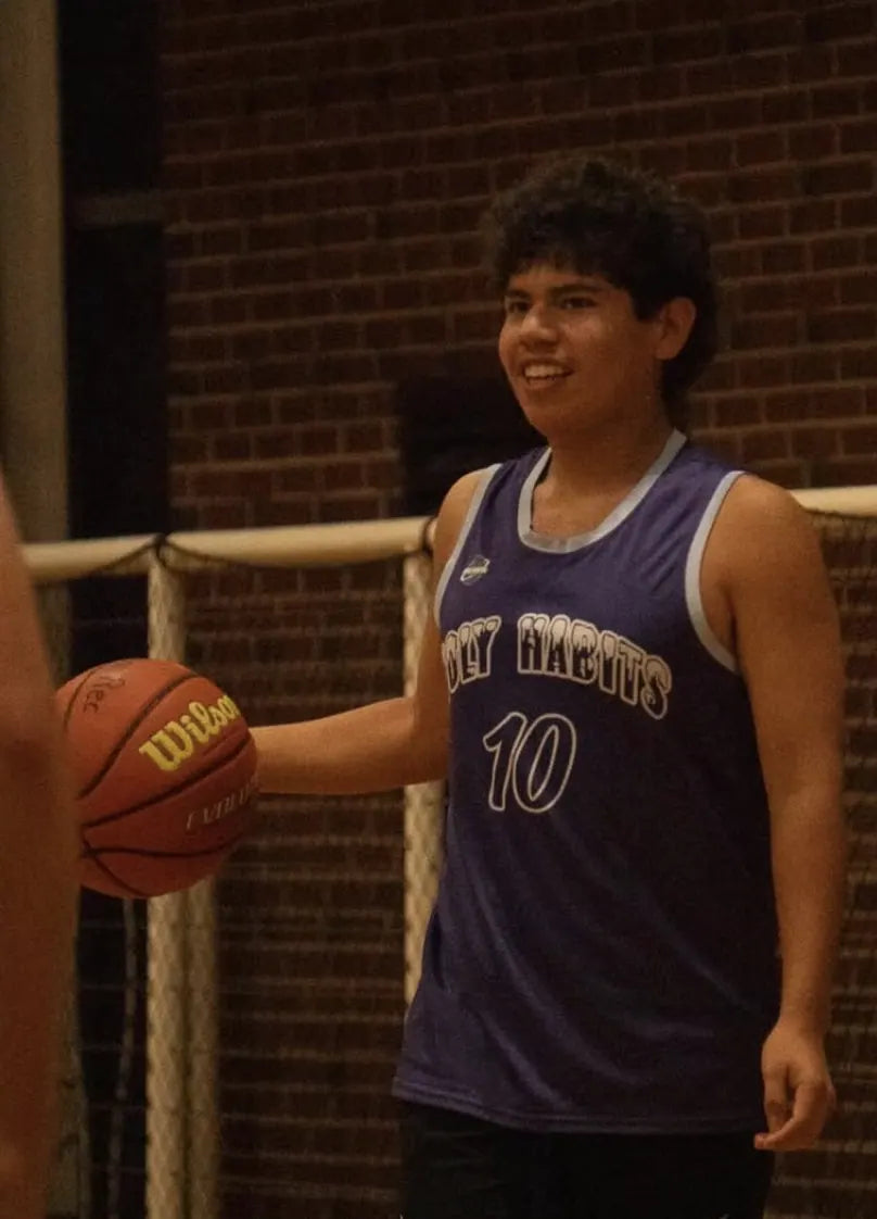 A basketball player in a purple Rich Habits jersey, number 10