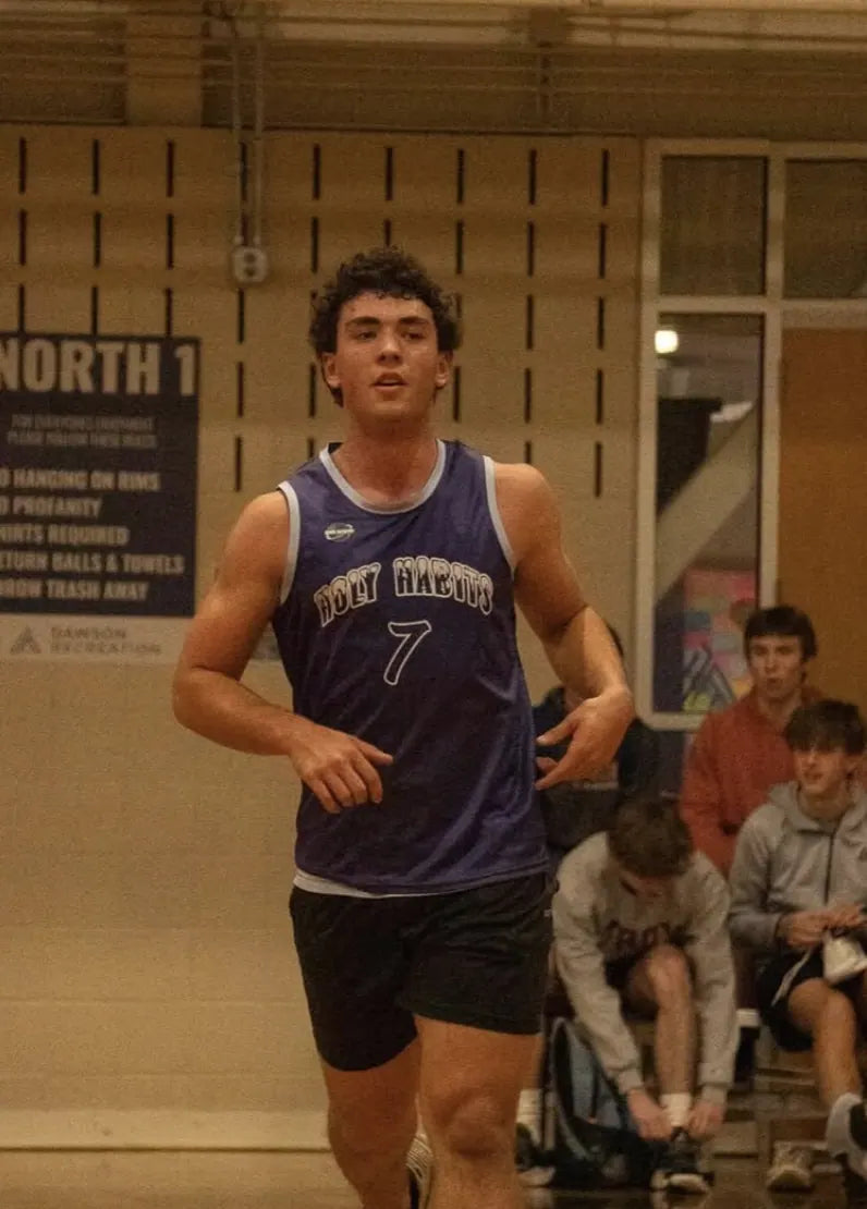 A basketball player in a purple Rich Habits jersey, number 7