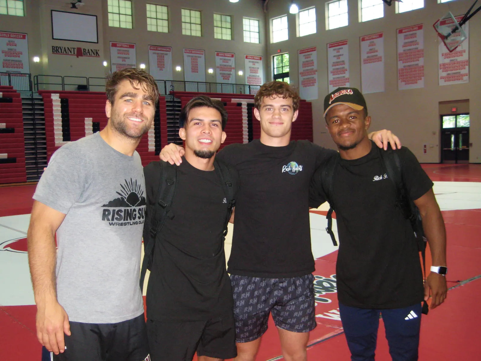 Sam Sutton with three clinicians on the mat in a high-school gym