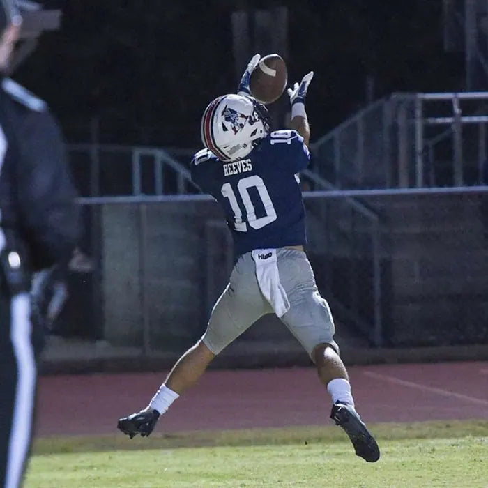 Charlie Reeves, number 10, fully extended to catch a pass under the lights