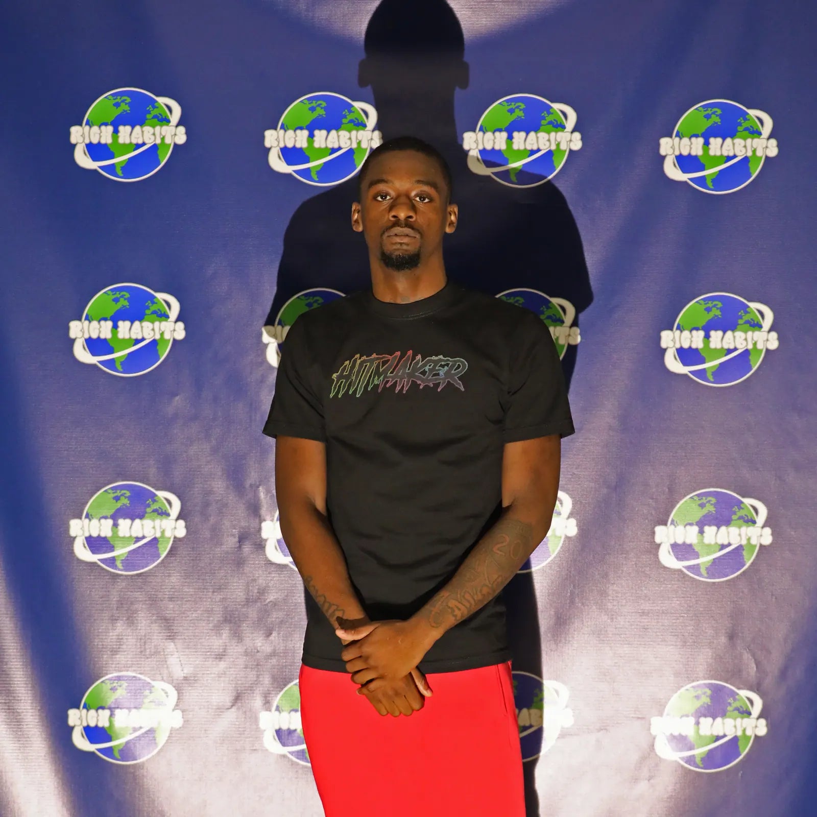 Luh Soldier in the Hitmaker tee in front of the globe backdrop