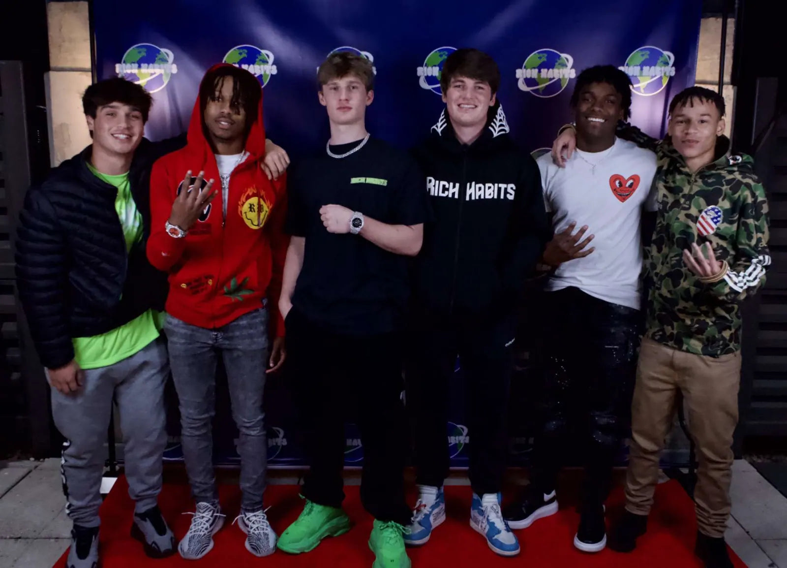 Six friends on the red carpet at the launch party, one in a Rich Habits tee