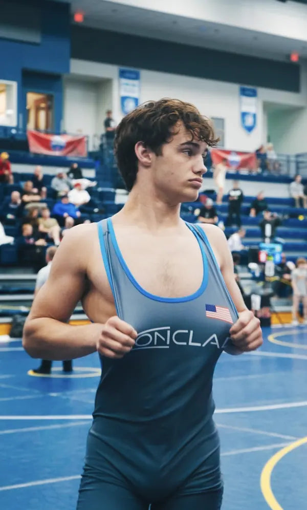 A young Sam Sutton in the Ironclad singlet at a tournament, gripping the straps