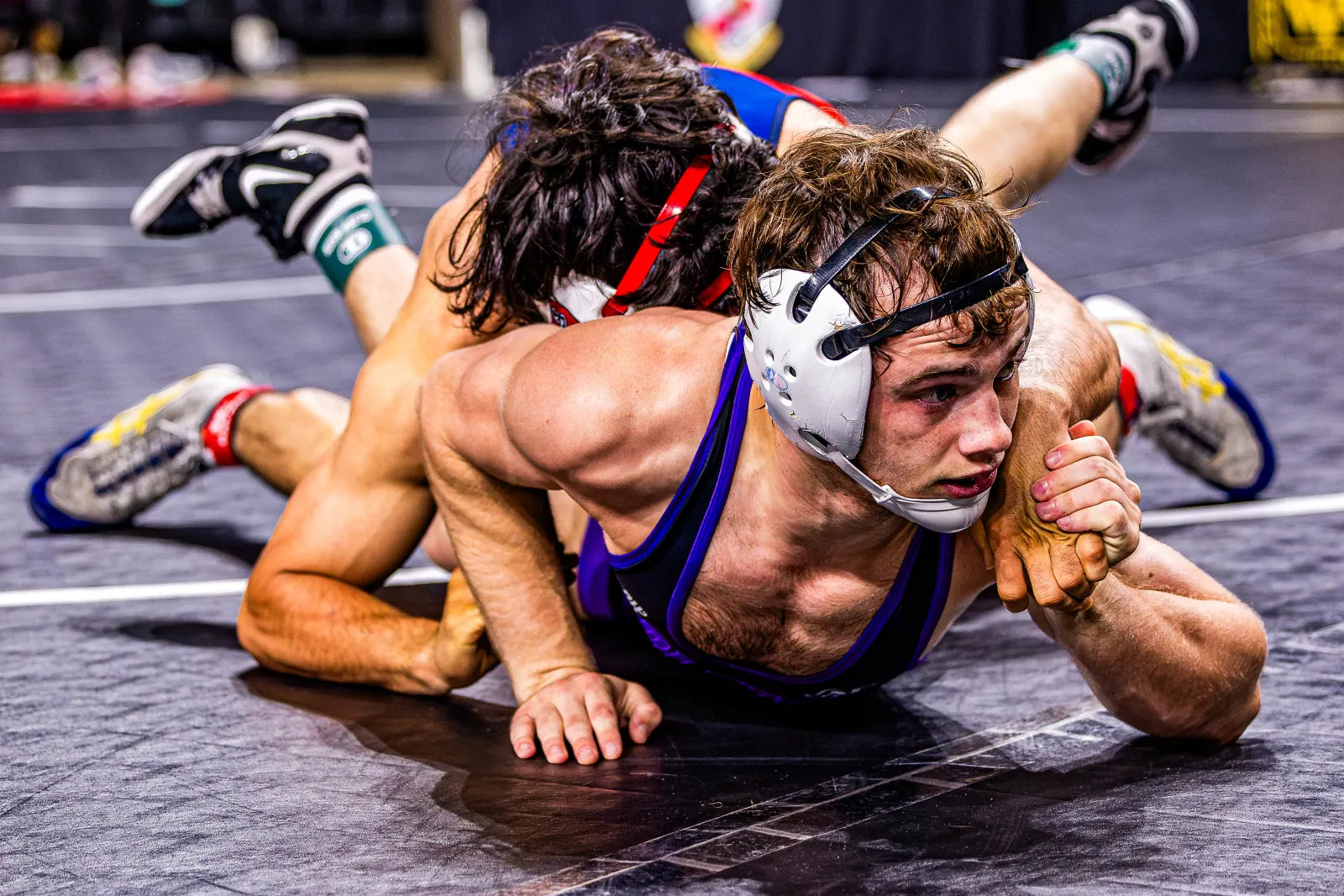 Sam Sutton on the mat in the purple Tarleton singlet, mid-scramble