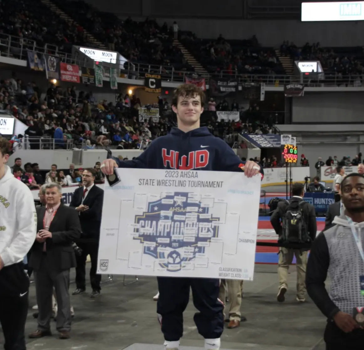Sam Sutton holding the 2023 AHSAA state bracket board in a Homewood hoodie