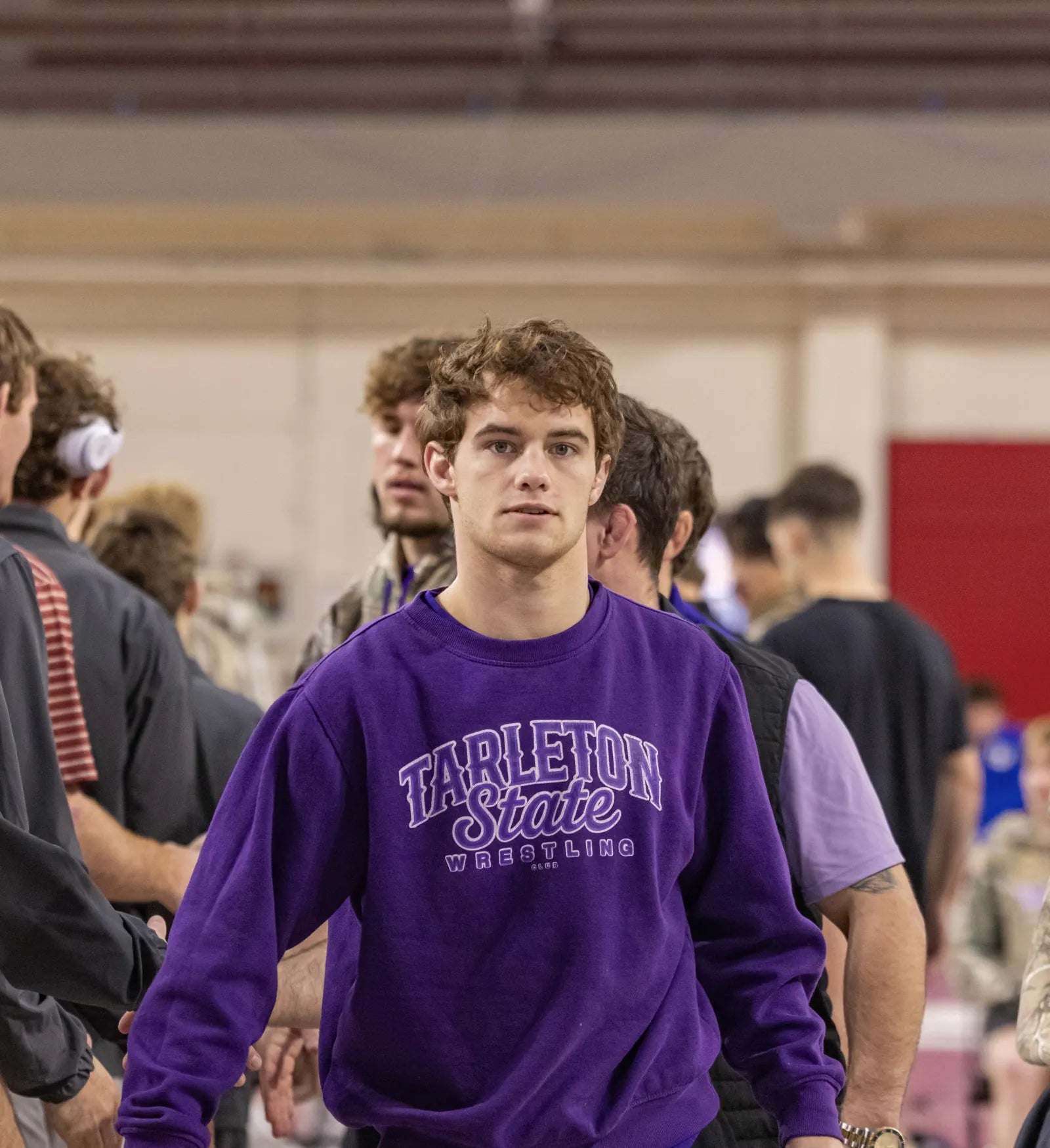 Sam Sutton in the purple Tarleton crewneck walking through a crowded gym