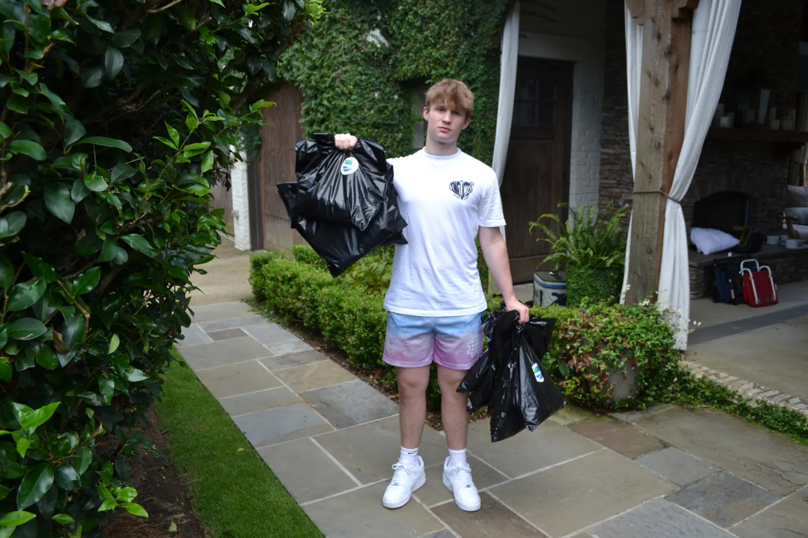 Carter Vail outdoors carrying two armfuls of black mailers