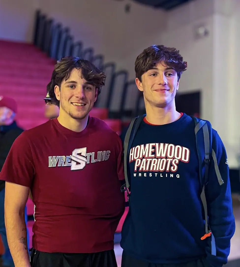 Two wrestlers after an event, one in a maroon Southside Wrestling tee and one in a navy Homewood Patriots crewneck
