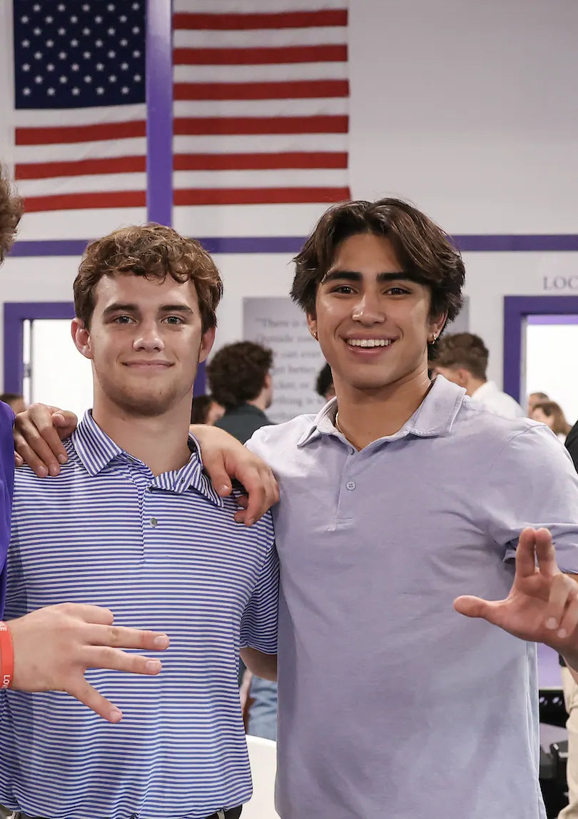 Nico Egbalic and Sam Sutton in polos under the American flag at the Tarleton wrestling room opening