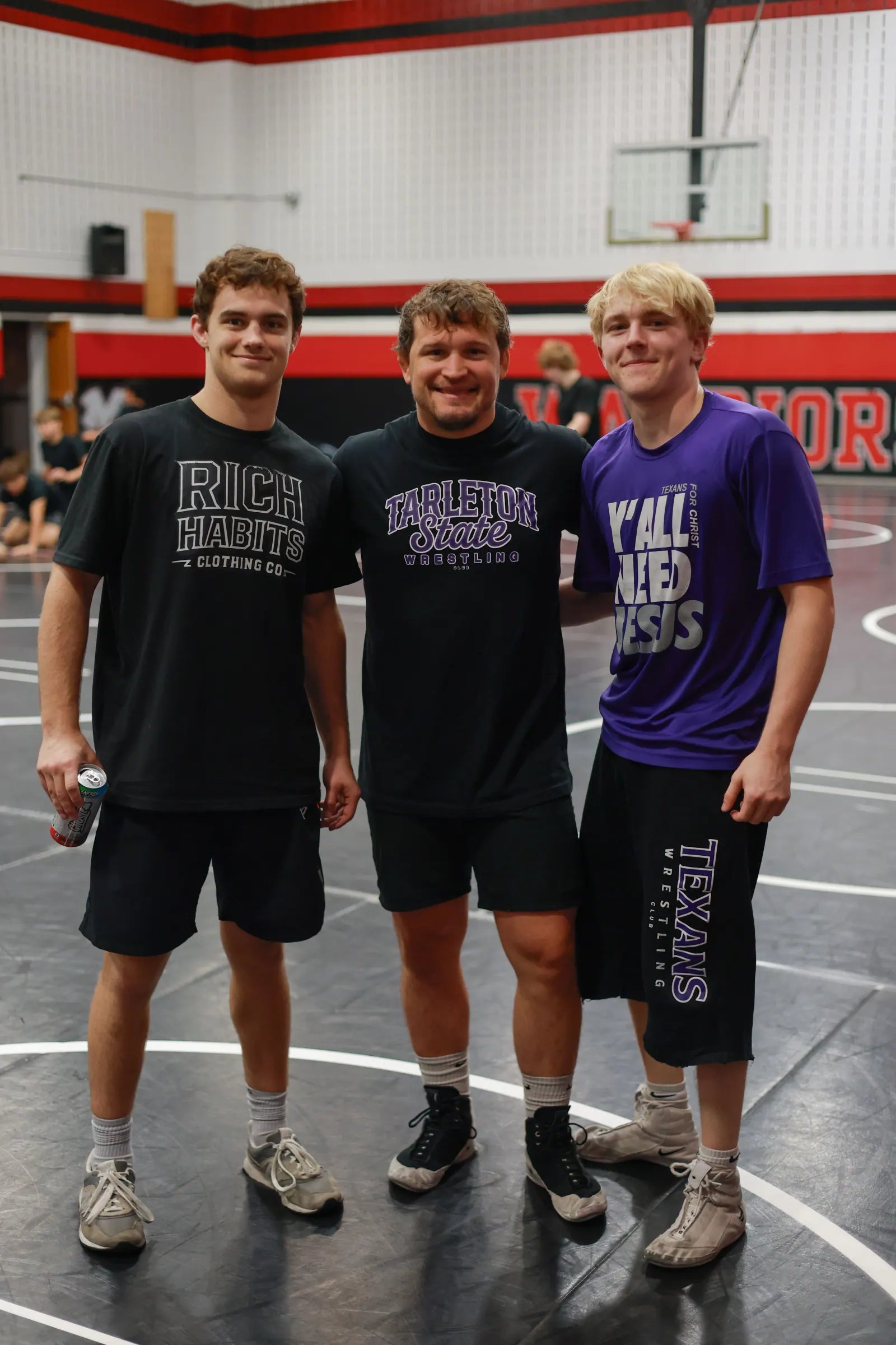 Sam Sutton in a Rich Habits tee with two coaches, one in a purple shirt that reads Y'all need Jesus