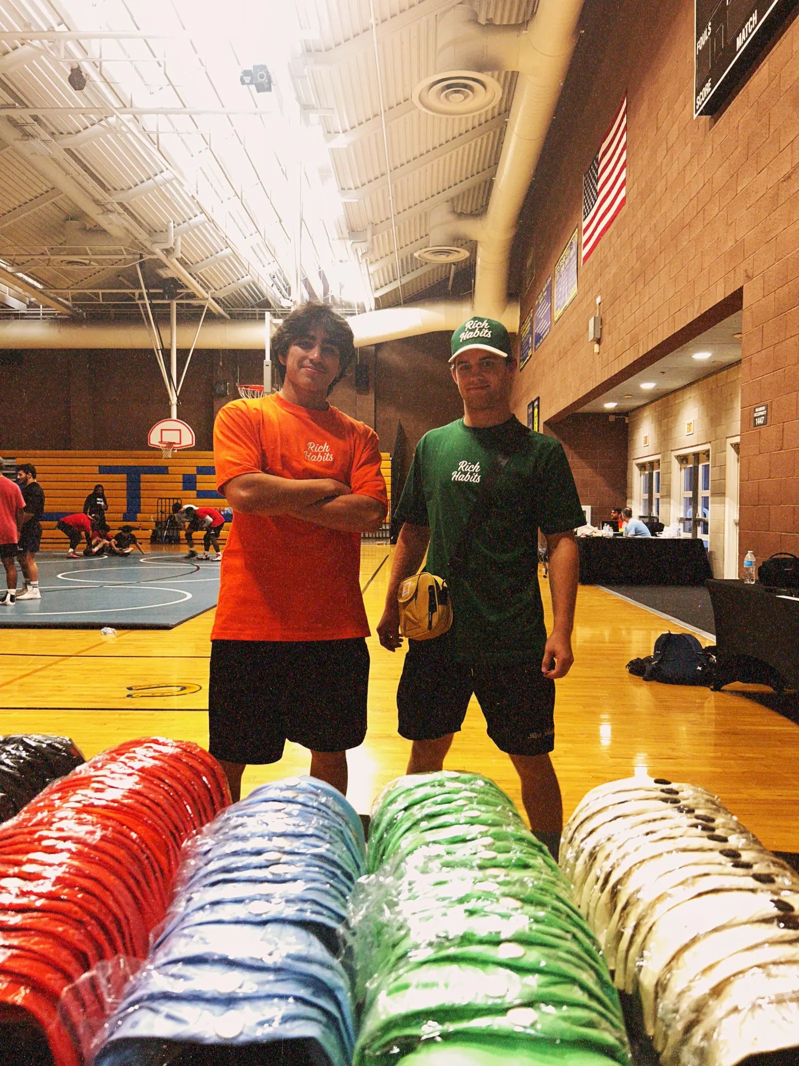 Sam Sutton and Nico Egbalic behind rows of Rich Habits caps laid out on a mat