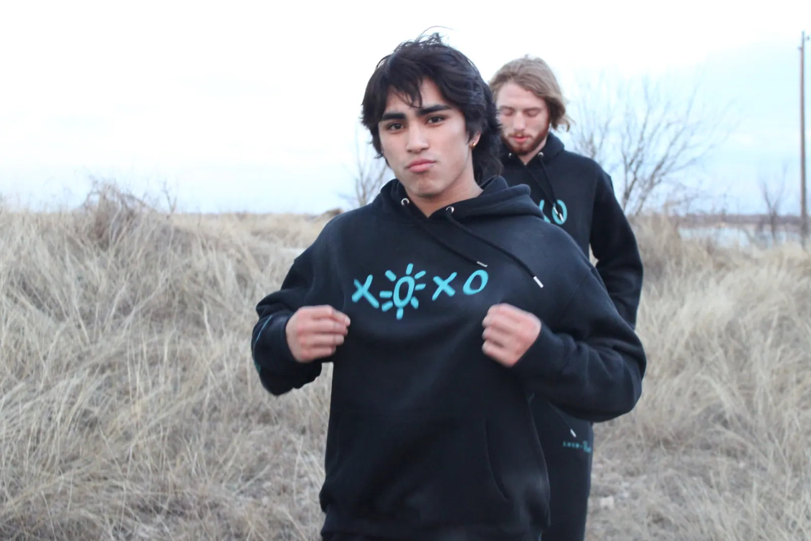 Nico Egbalic in an XOXO Reece hoodie standing in winter grass